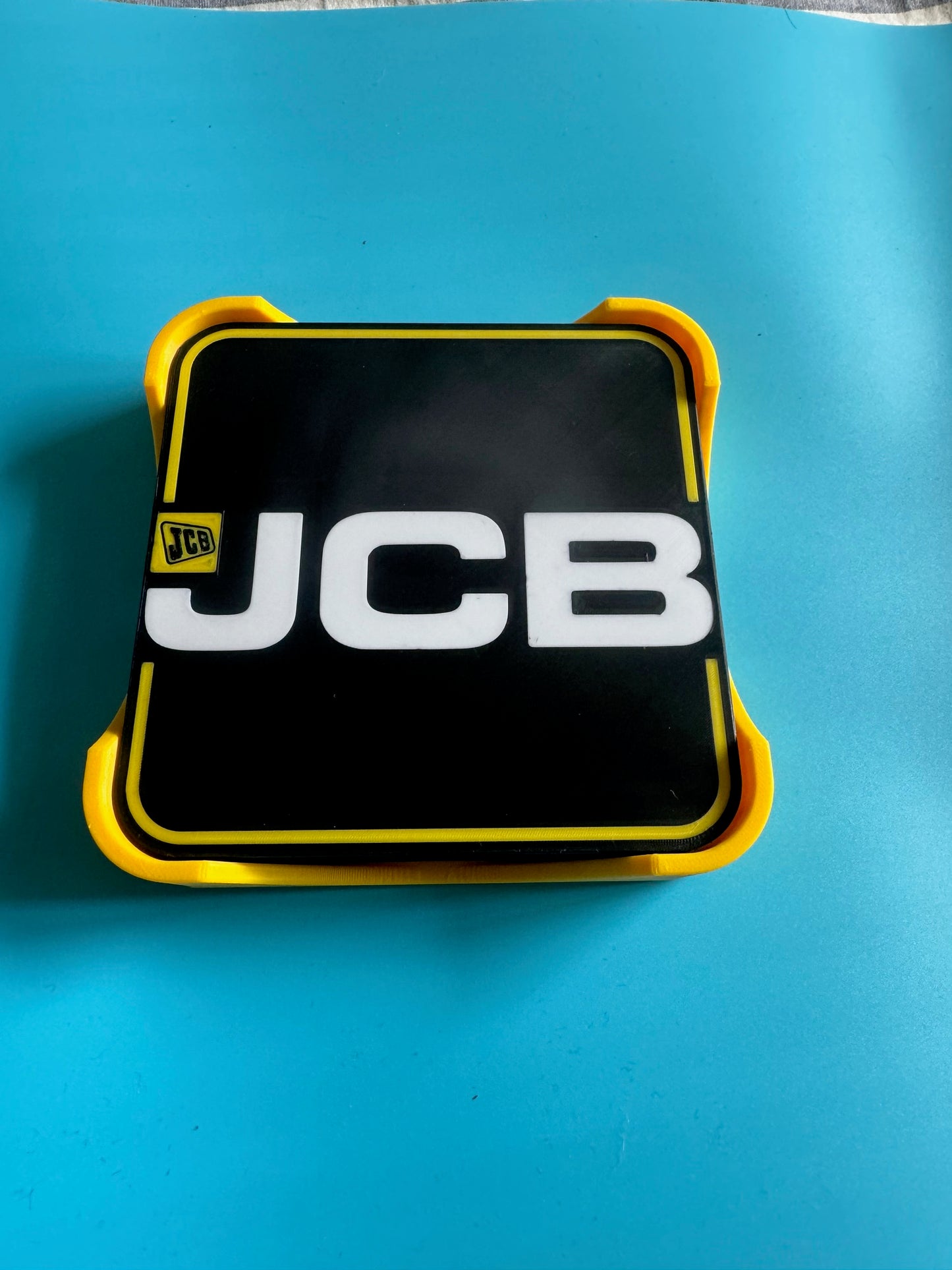 JCB logo on a black and yellow rectangular object against a blue background