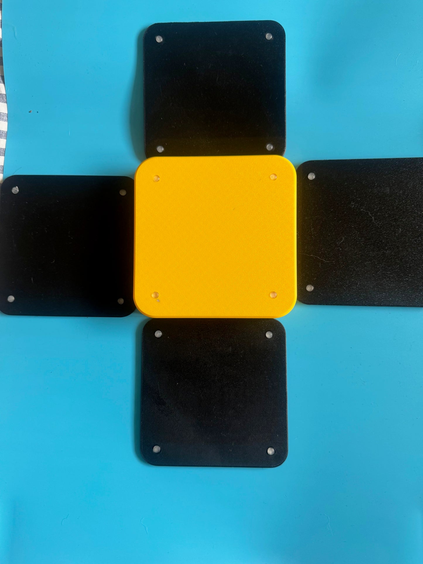 Yellow square with black square attachments on a blue background
