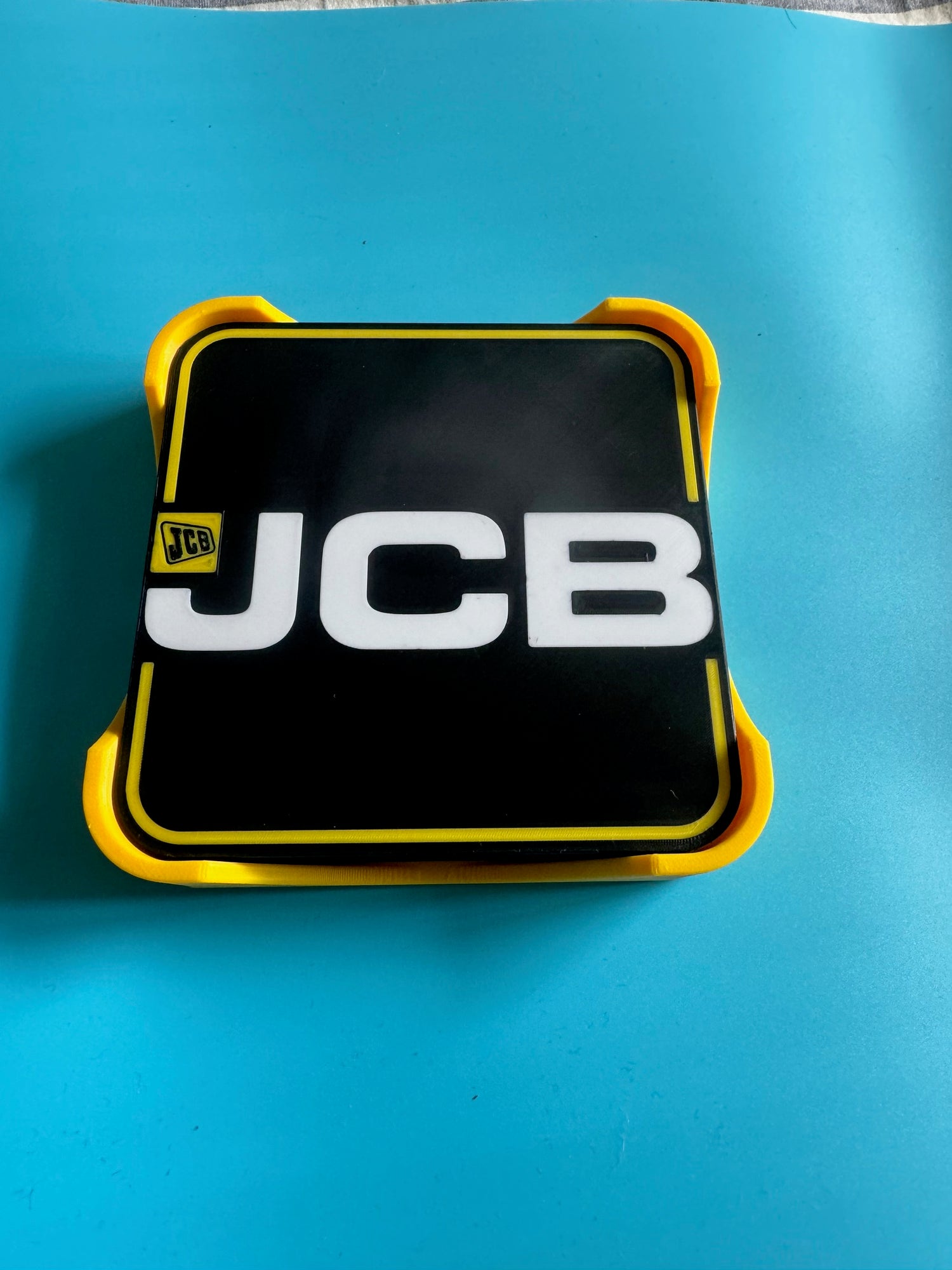 JCB logo on a black and yellow rectangular object against a blue background
